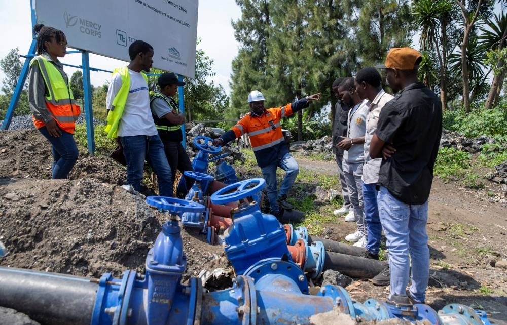 Yves Ntaboba, Technical Director of Yme Jibu, explains the water connection system to visiting students at the reservoir, where construction has stalled due to USAID funding cuts to the NGO Mercy Corps, in Goma, North Kivu province, Democratic Republic of Congo, June 16, 2025. REUTERS/Arlette Bashizi