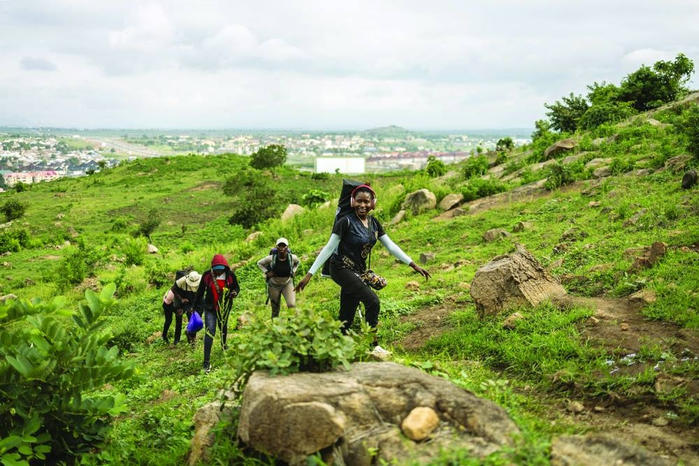 A hiker leads a group along a rocky path as they climb a hill during a group hike on the outskirts of Abuja, Nigeria.