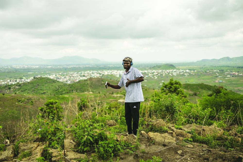 A man dances while listening to music at the summit of a hill during a group hike on the outskirts of Abuja.