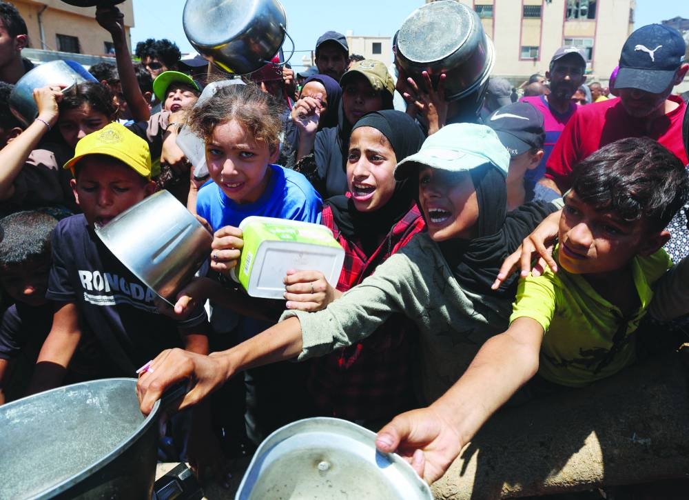 
Palestinians gather to receive food from a charity kitchen, amid a hunger crisis, in Nuseirat, central Gaza Strip, yesterday. 
