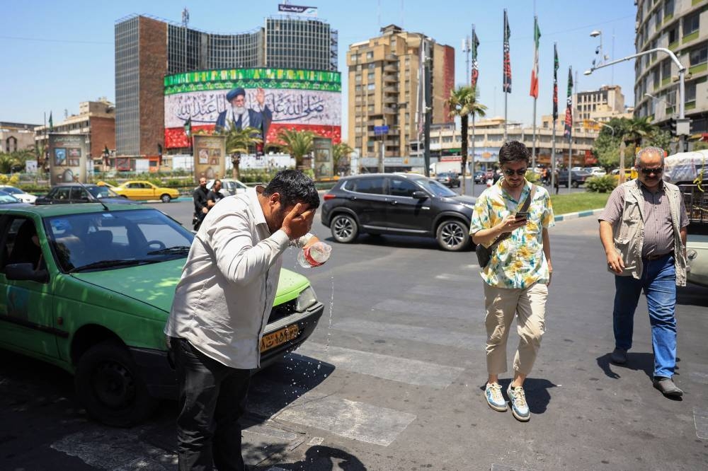 An Iranian taxi driver cools down by splashing water on his head on a street amid soaring temperatures in Tehran on July 22, 2025. Iranian authorities have urged residents to limit water consumption as the country grapples with severe shortages amid an ongoing heatwave, local media reported. On July 19, the national meteorological service said Iran was experiencing its hottest week of the year so far, with temperatures exceeding 50 degrees Celsius (122 Fahrenheit) in some areas. (Photo by AFP)