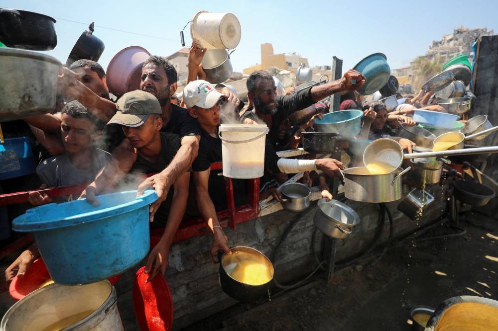Palestinians gather to receive food from a charity kitchen, amid a hunger crisis, in Gaza City, yesterday.