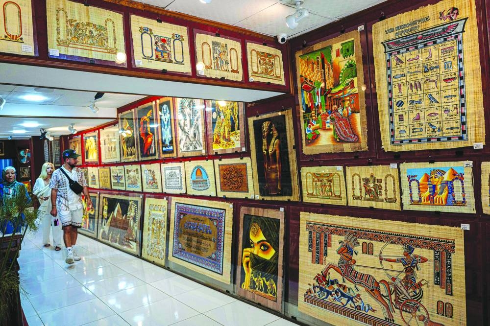 File photo shows tourists visit a papyrus shop near the Great Pyramids plateau in Giza, south of Cairo.