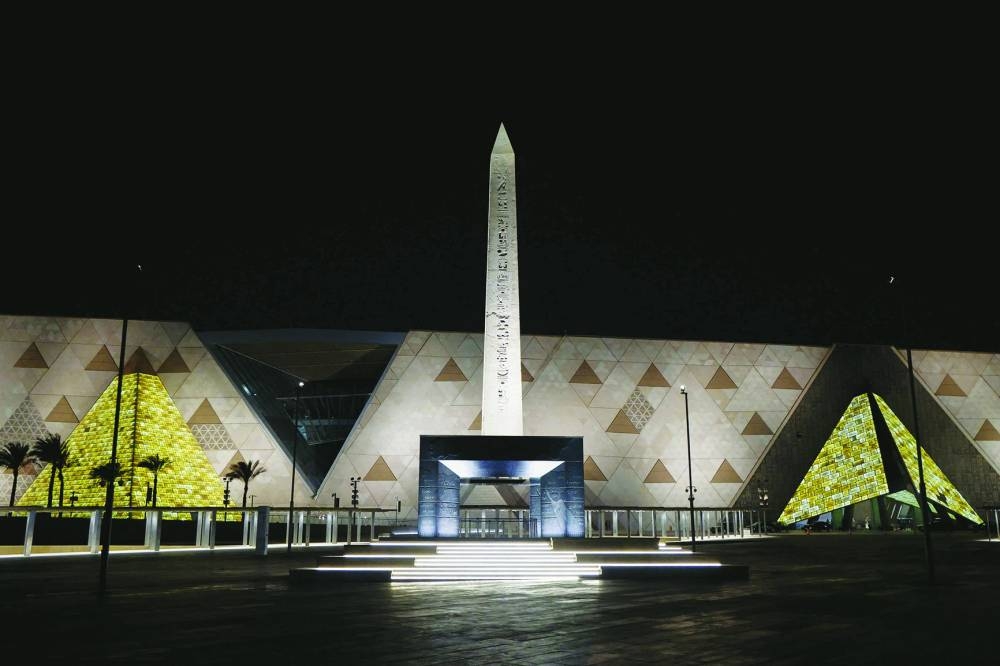 (FILES) The Obelisk of Ramses II is pictured before the facade and entrance of the new Grand Egyptian Museum in Giza near Cairo late on April 6, 2025. The museum was expected to attract up to five mn visitors annually, fuelling optimism across Cairo's battered tourism sector. But less than three weeks before its July 3 opening, the government announced another delay, this time pushing the landmark event to the final quarter of the year. (Photo by Ludovic MARIN / POOL / AFP)