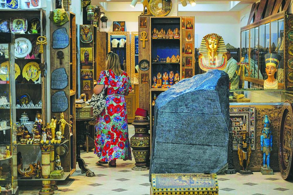 (FILES) A tourist visits Philae Jewellery Bazaar shop near the Great Pyramids plateau in Giza, south of Cairo, on June 10, 2025. The museum was expected to attract up to five mn visitors annually, fuelling optimism across Cairo's battered tourism sector. But less than three weeks before its July 3 opening, the government announced another delay, this time pushing the landmark event to the final quarter of the year. (Photo by Khaled DESOUKI / AFP)