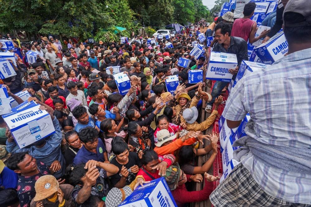 People gather to receive water supplies amid ongoing clashes on the Thai-Cambodian border, in Oddar Meanchey province, Cambodia, yesterday