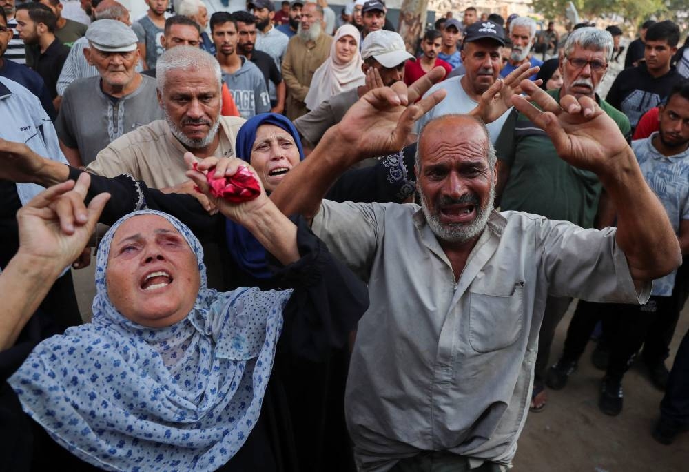 People mourn at a funeral of Palestinians killed by Israeli fire while trying to receive aid and others who were killed in an overnight Israeli strike, at Al-Shifa Hospital in Gaza City, yesterday.