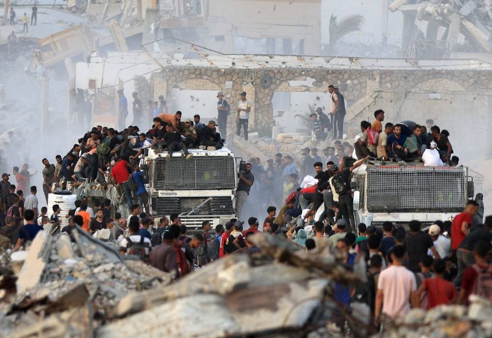 Palestinians climb onto trucks carrying aid supplies that entered Gaza through Israel, in Beit Lahia, in the northern Gaza Strip, Tuesday.