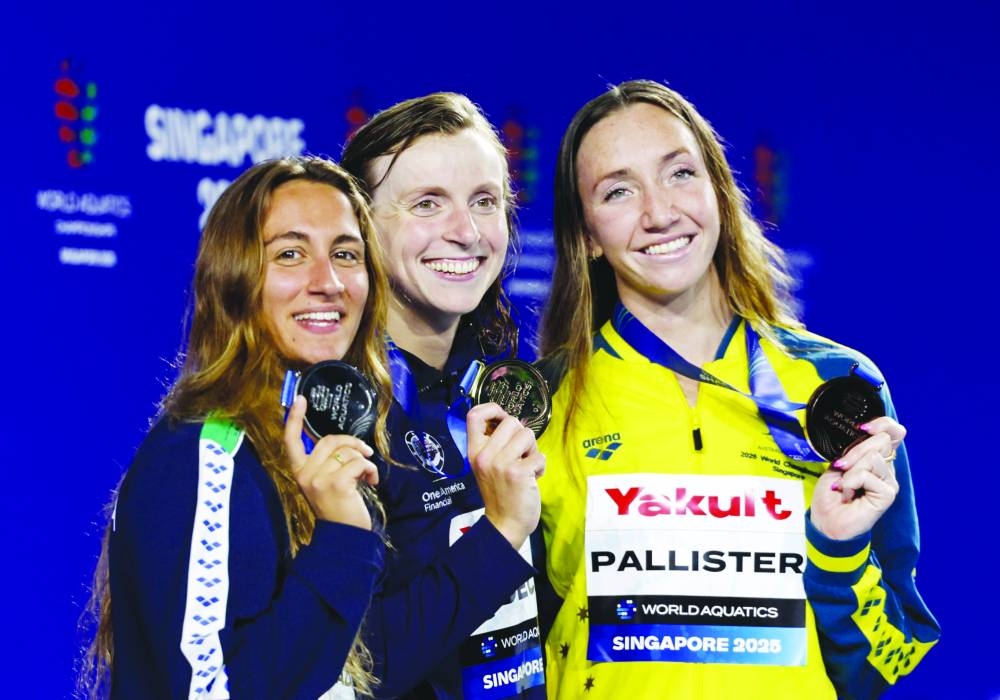Swimming - World Aquatics Championships - Women 1500m Freestyle Final - World Aquatics Championships Arena, Singapore - July 29, 2025 Gold medallist Katie Ledecky of the U.S. celebrates on the podium after winning the final with silver medallist Italy's Simona Quadarella and bronze medallist Australia's Lani Pallister REUTERS/Tingshu Wang