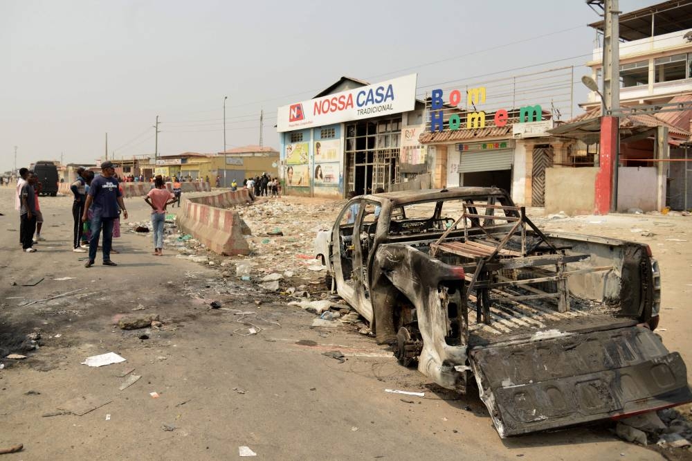 Residents walk past a looted supermarket in the Kalemba 2 district of Luanda during a general strike in the taxi sector,  to protest against the rising prices of fuel.
