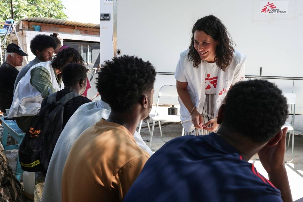 Midwife Valentina Cerasaro, 35, talks with refugees waiting outside the MSF mobile clinic, at the Parea community centre, a hub for organisations working on the island ran by Europe Care, near Mavrovouni, Lesbos island. (Reuters)