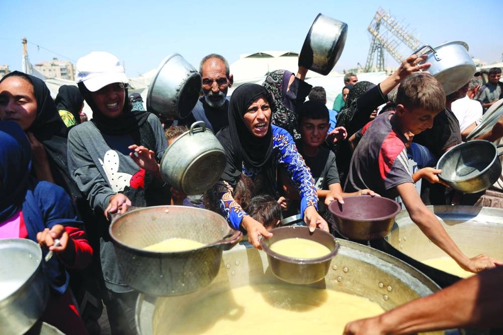 
Palestinians receive lentil soup at a food distribution point in Gaza City yesterday. 