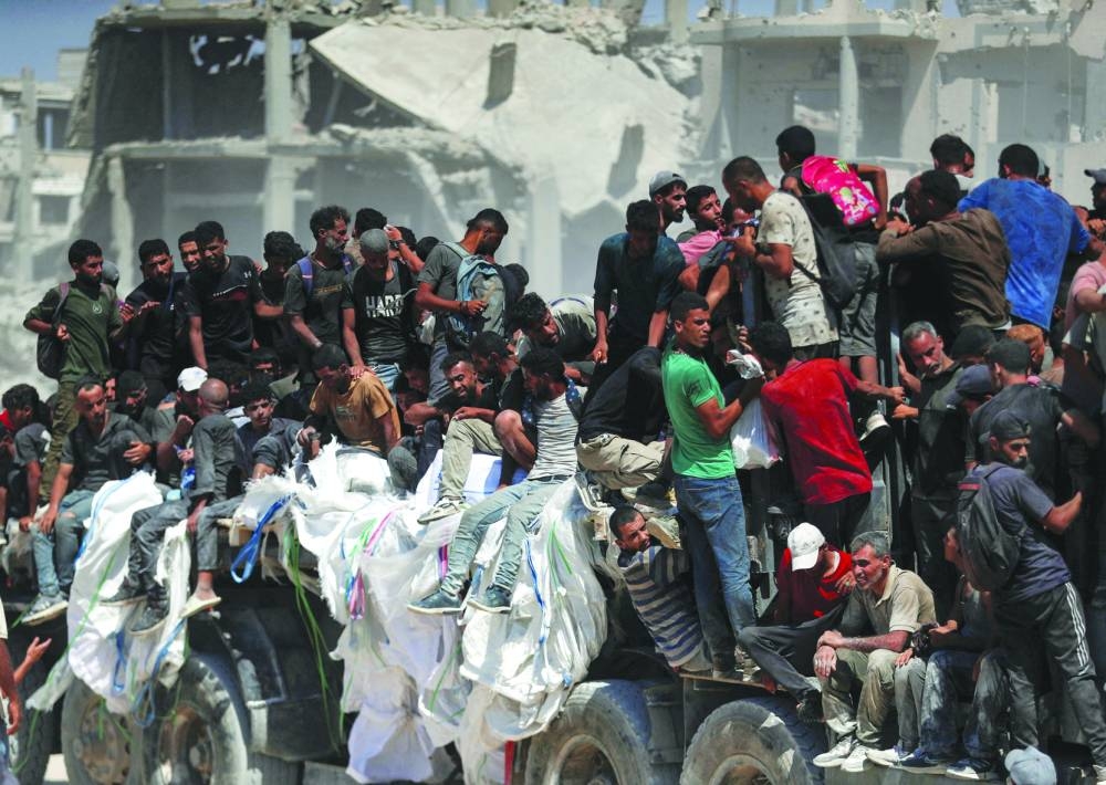 
Palestinians climb onto a truck as they seek for aid supplies that entered Gaza through Israel in Beit Lahia, northern Gaza Strip, yesterday. 