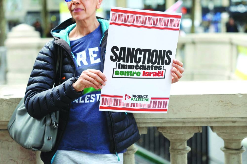 A protester holds a placard demanding "Immediate sanctions against Israel" during a pro-Palestinian gathering in Paris, Saturday.