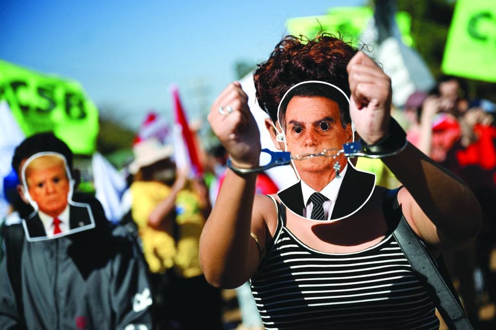 Protesters are seen wearing masks depicting former president Jair Bolsonaro and US President Donald Trump in front of the US embassy in Brasilia. – Reuters