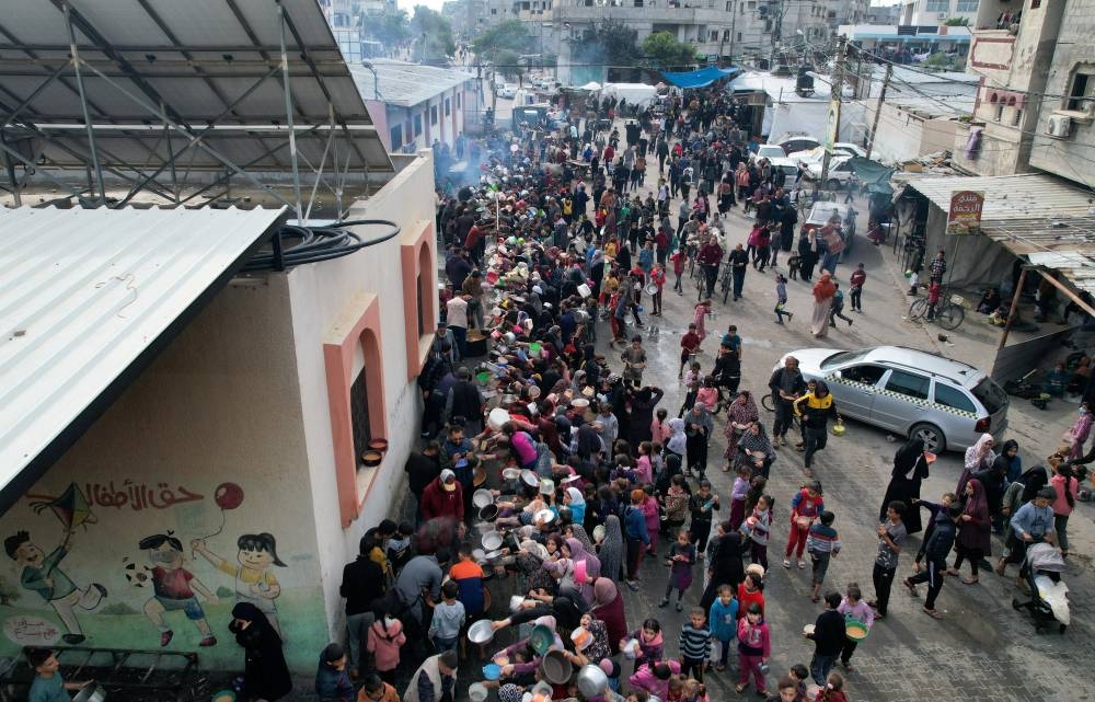 Palestinians gather to receive food cooked by a charity kitchen in Rafah in the southern Gaza Strip, on Sunday. REUTERS