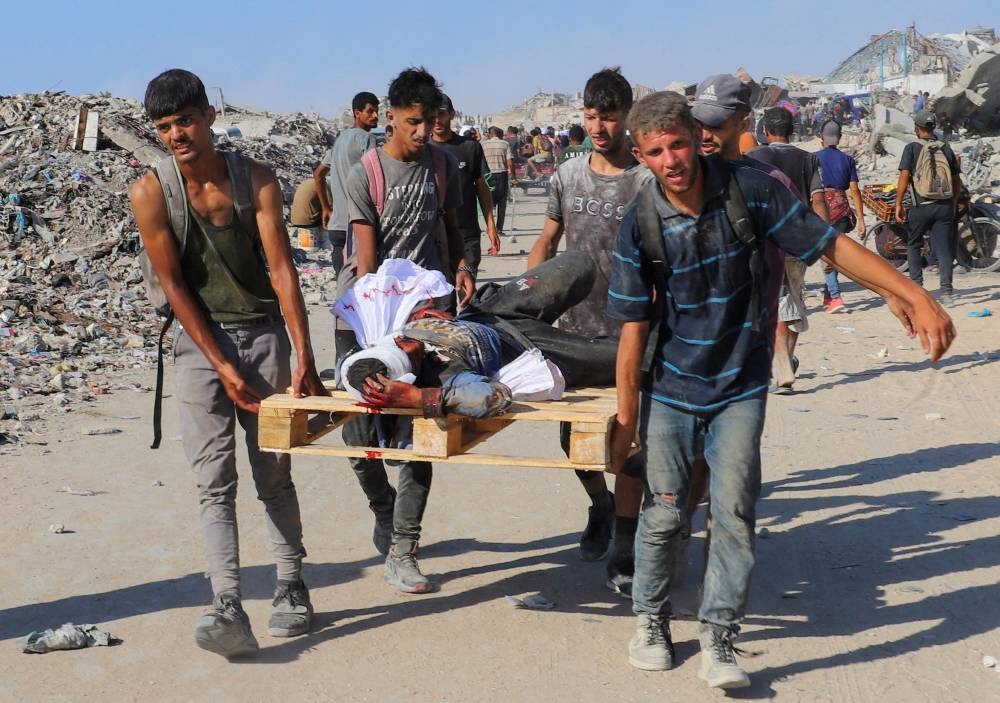Palestinians carry a person wounded by Israeli fire, on a pallet, after aid supplies that entered Gaza through Israel arrived, in Beit Lahia, northern Gaza Strip, on Sunday. REUTERS