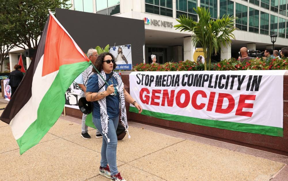 A demonstrator carries a Palestinian flag during a press conference held at a Gaza media encampment set up outside major media offices in Washington, DC, Tuesday.