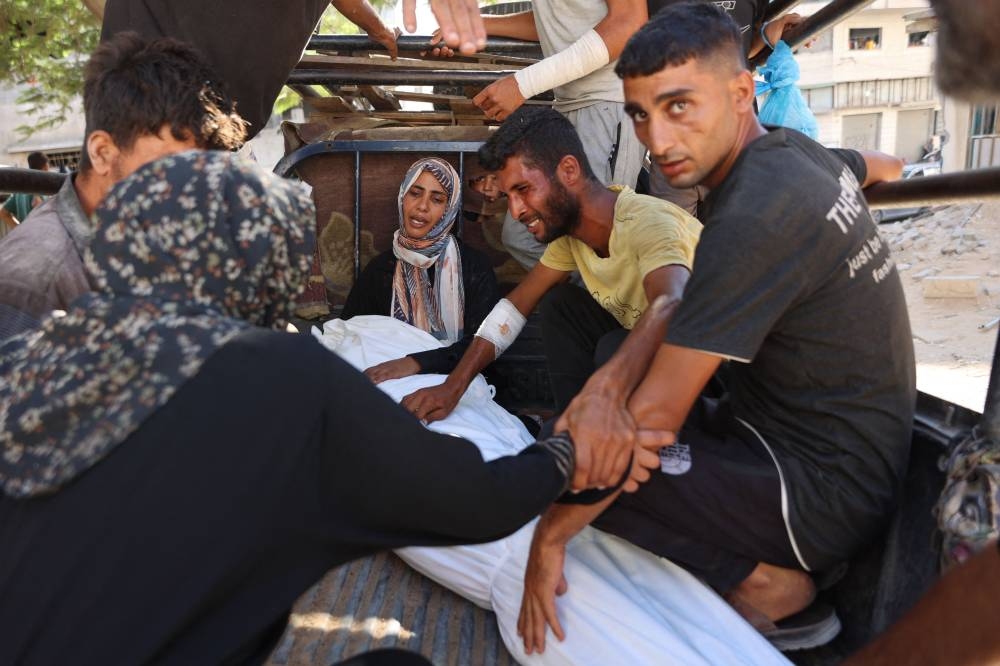 Palestinians mourn a relative, who was killed while seeking aid at the Zikim crossing, ahead of their funeral at Al-Shifa hospital in Gaza City, on Tuesday. AFP