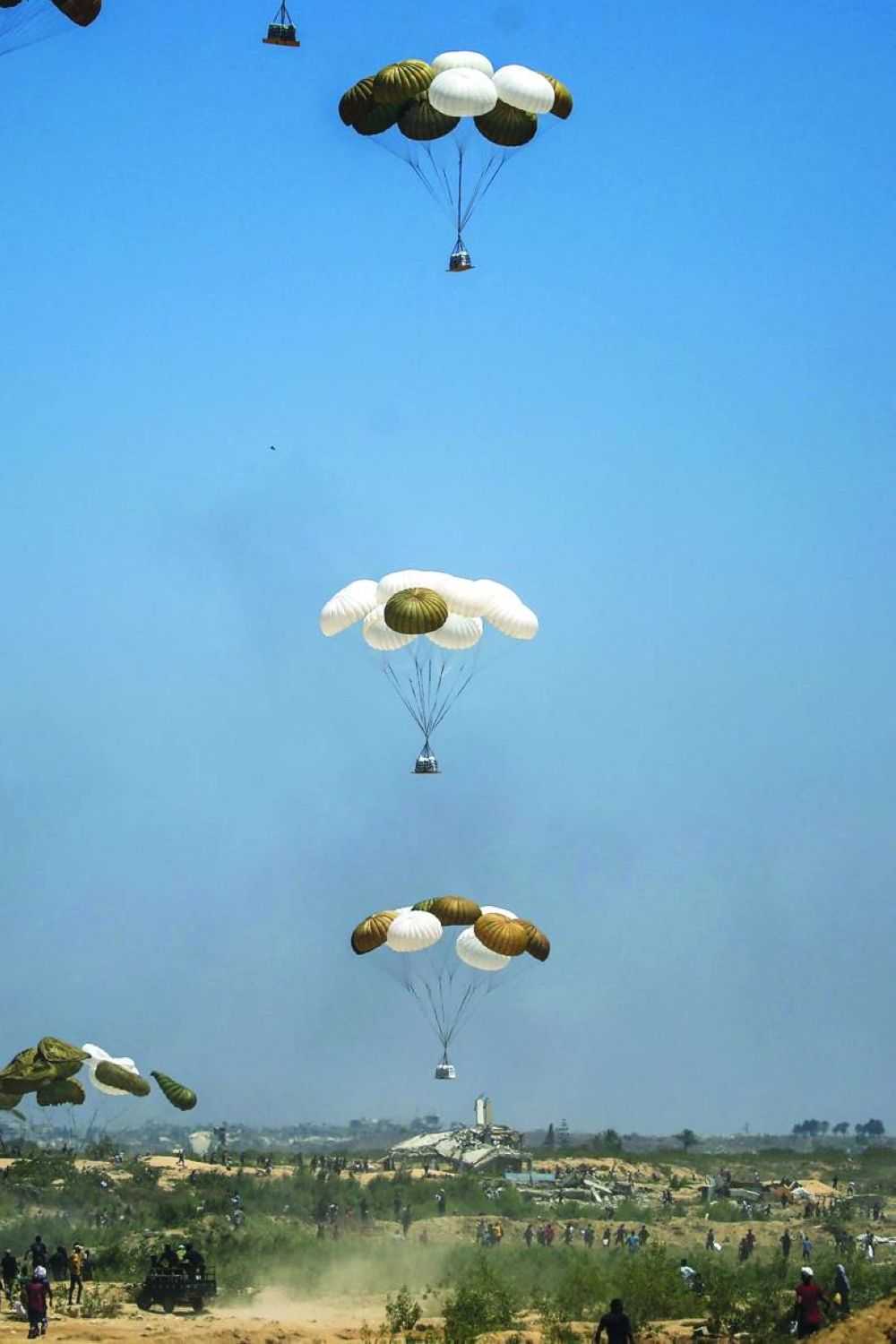 Palestinians rush to retrieve aid packages parachuted during an airdrop over Nuseirat in the central Gaza Strip Wednesday.