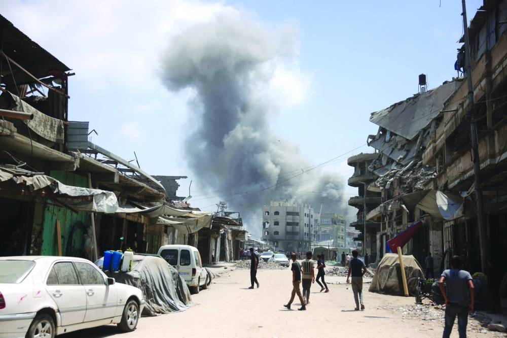 Palestinian watch as a plume of smoke rises during an Israeli strike on Gaza City's southern al-Zeitoun neighbourhood Friday.