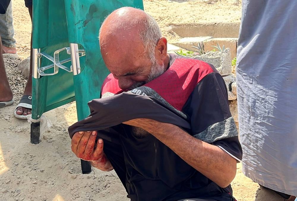 The father of Palestinian boy Muhannad Eid, who died after being struck by a box of airdropped aid, reacts during his son's funeral, in Nuseirat, in the central Gaza Strip, on Saturday. REUTERS