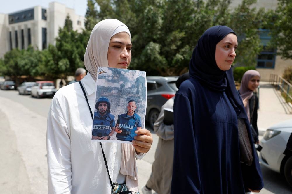 A Palestinian woman holds up a print-out of a photograph as they protest against the killing of journalists in Gaza, at Birzeit University near Ramallah in occupied West Bank, Monday.