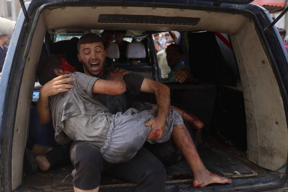 A Palestinian man carries a wounded youth, evacuated from the site of an Israeli strike, west of Gaza City on August 12, 2025. Gaza's civil defence agency said Israeli air strikes on Gaza City have intensified in recent days, following Israel PM's security cabinet approving plans to expand the war there. (AFP)