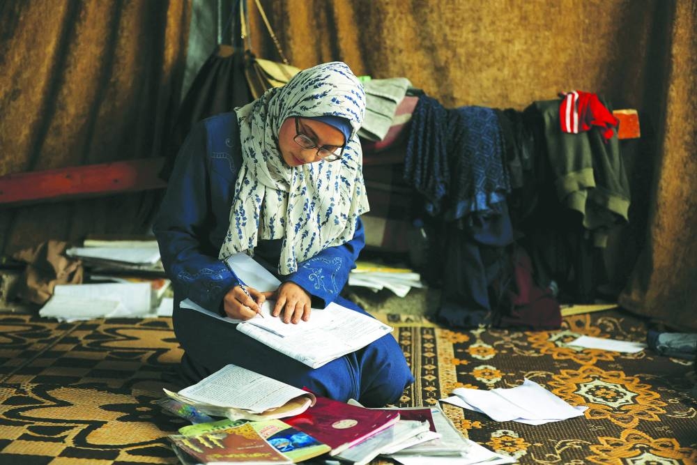 Displaced 19-year-old Palestinian student of Gaza's Azhar Institute, Saja Adwan, studies at a damaged school building being used as a shelter for displaced families, in Gaza City.