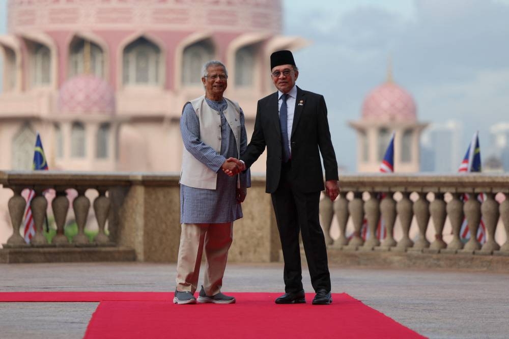 Chief adviser of Bangladesh's interim government Muhammad Yunus (left) shakes hands with Malaysian Prime Minister Anwar Ibrahim during a welcome ceremony in Putrajaya Tuesday