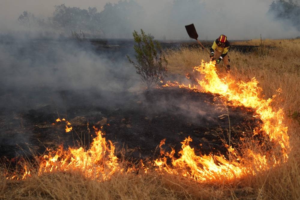 A firefighter works to extinguish a wildfire approaching Losacio, north of Zamora, on August 12, 2025. A man died from burns and thousands of people were forced to evacuate as wildfires swept through parts of Spain, fueled by strong winds and a searing heat wave that has gripped the country for 10 days. (AFP)