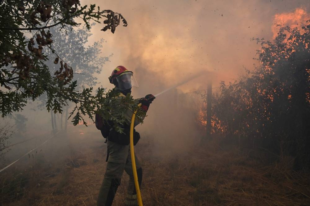 A firefighter works to extinguish a wildfire in San Cibrao das Viñas, outside Ourense, northwestern Spain, on August 12, 2025. A man died from burns and thousands of people were forced to evacuate as wildfires swept through parts of Spain Tuesday, fueled by strong winds and a searing heat wave that has gripped the country for 10 days. (AFP)