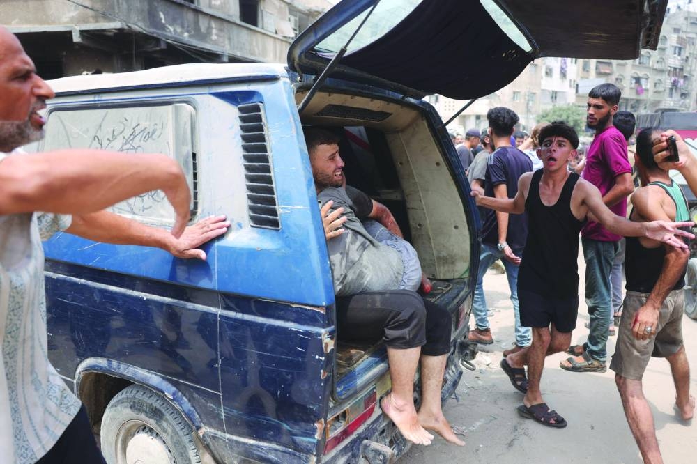 A Palestinian man carries a wounded youth, evacuated from the site of an Israeli strike, west of Gaza City on Tuesday.