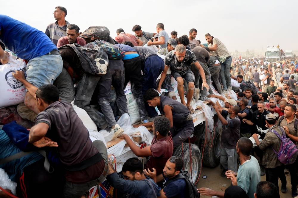 Palestinians scramble to collect aid supplies from trucks that entered through Israel, in Khan Younis, southern Gaza Strip, on Tuesday. REUTERS