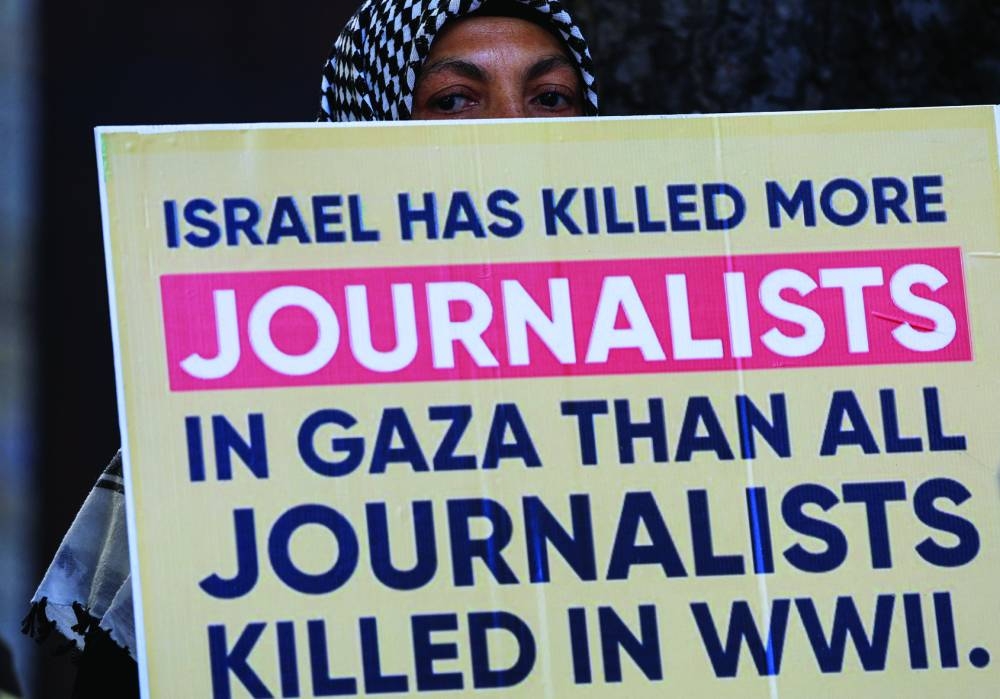 A person holds a placard during a vigil in solidarity with journalists killed in Gaza, outside St George’s Cathedral in Cape Town, South Africa, Wednesday.