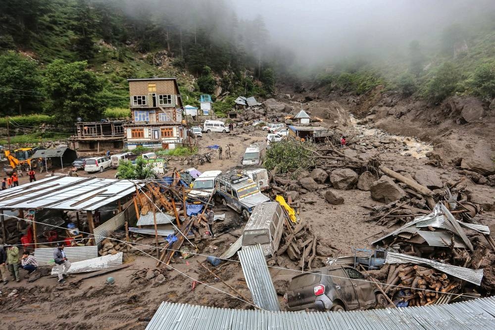 Damaged houses and vehicles are seen at the site of a flash flood at a village in Kishtwar district Friday.