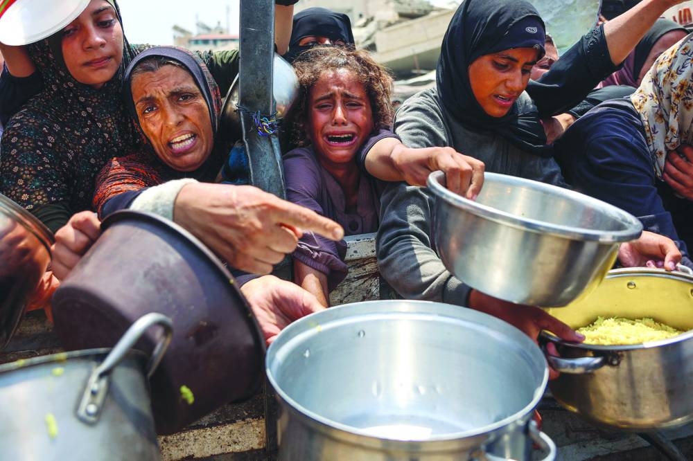 A Palestinian girl cries as she tries to receive cooked meals along with others from a food distribution center in Gaza City.