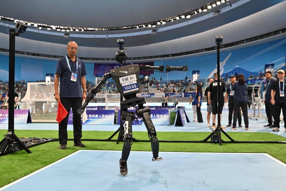 A robot falls while competing in a high jump event during the World Humanoid robots games in Beijing on August 16, 2025. (AFP)