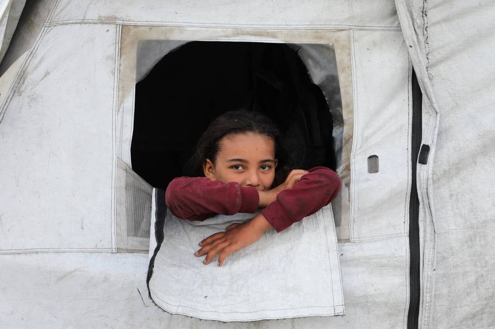 A displaced Palestinian girl looks out of her family tent where she shelters as the Israeli military prepares to relocate residents to southern Gaza, in Gaza City, August 18, 2025. (REUTERS)