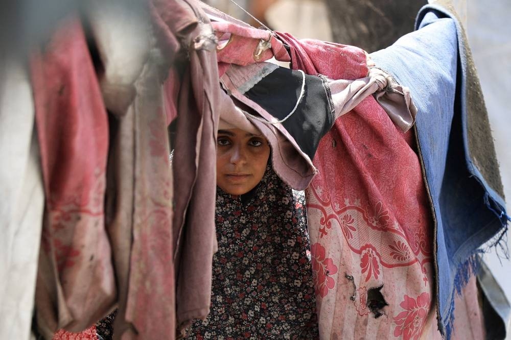 A Palestinian woman, displaced by the Israeli offensive, shelters in a tent camp as the Israeli military prepares to relocate residents to southern Gaza, in Gaza City. (REUTERS)
