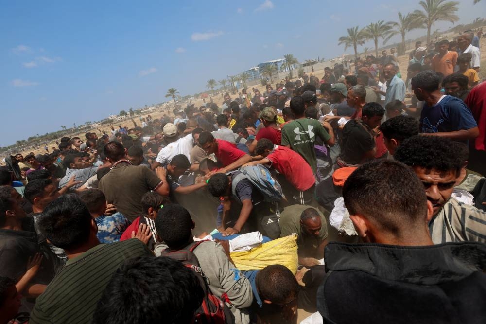 Palestinians gather to receive aid packages, in Deir Al-Balah, in the central Gaza Strip on Monday. REUTERS