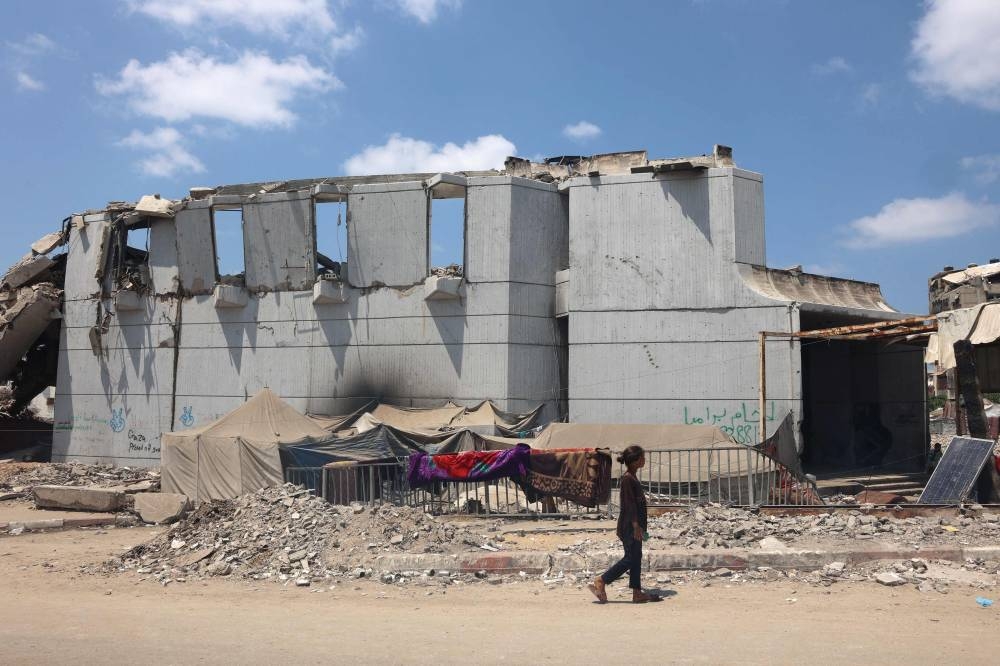 A Palestinian girl walks past the destroyed Rashad al-Shawa cultural center in Gaza City on August 18, 2025. (AFP)
