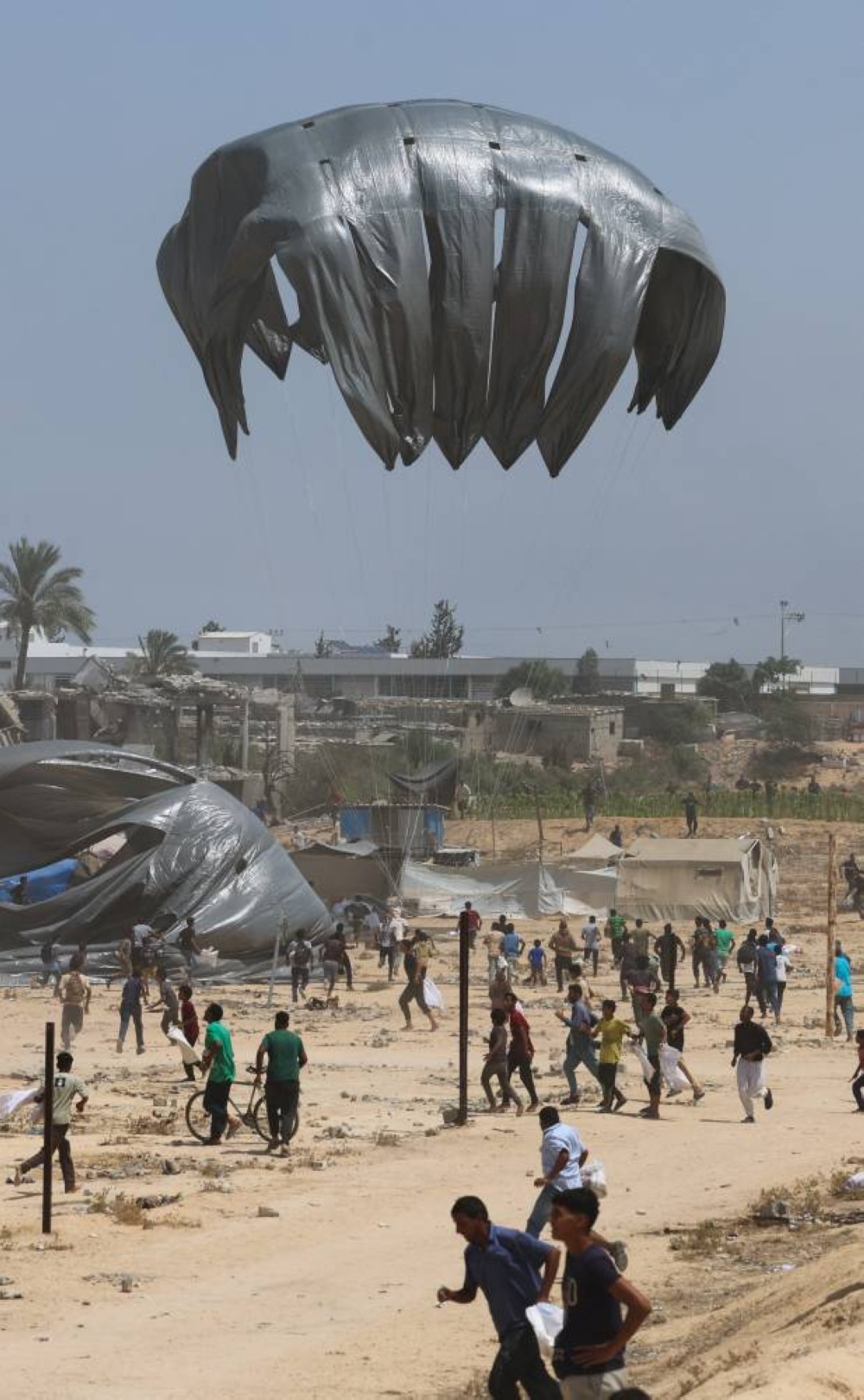 Palestinians run towards airdropped aid packages, in Deir Al-Balah, in the central Gaza Strip August 19, 2025. (REUTERS)