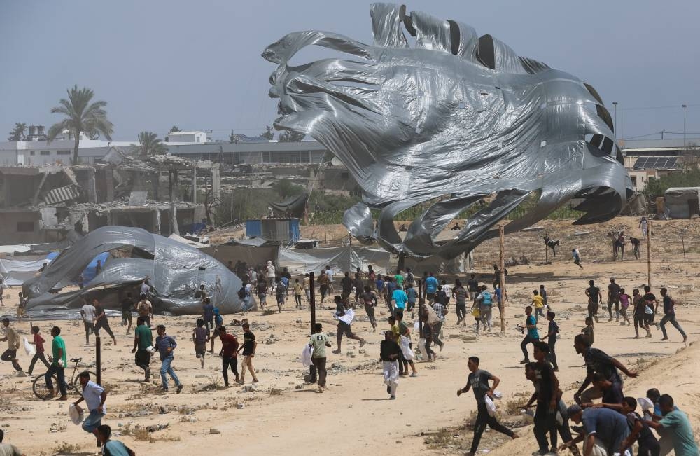 Palestinians run towards airdropped aid packages, in Deir Al-Balah, in the central Gaza Strip August 19, 2025. (REUTERS)