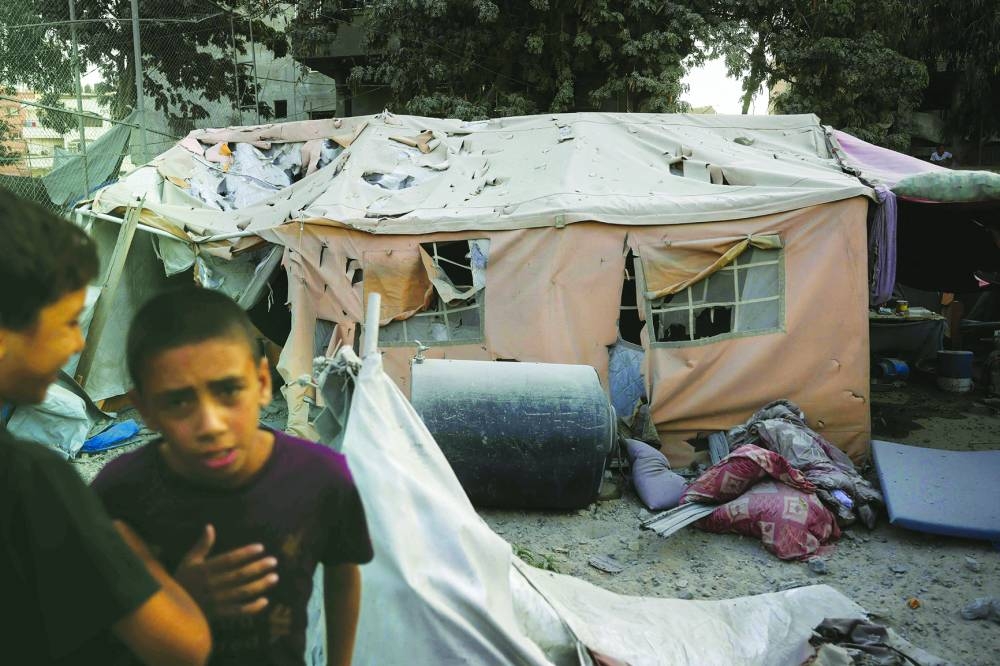 Palestinian youths gather near a damaged displacement tent following an Israeli strike on a six-storey building in the Saftawi neighborhood west of Jabalia in the northern Gaza Strip.