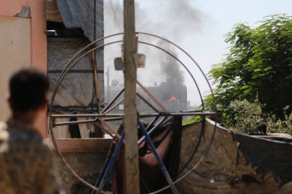A Palestinian man watches as a fire burn inside a building after an Israeli strike in Jabalia in the northern Gaza Strip on August 20, 2025. (AFP)