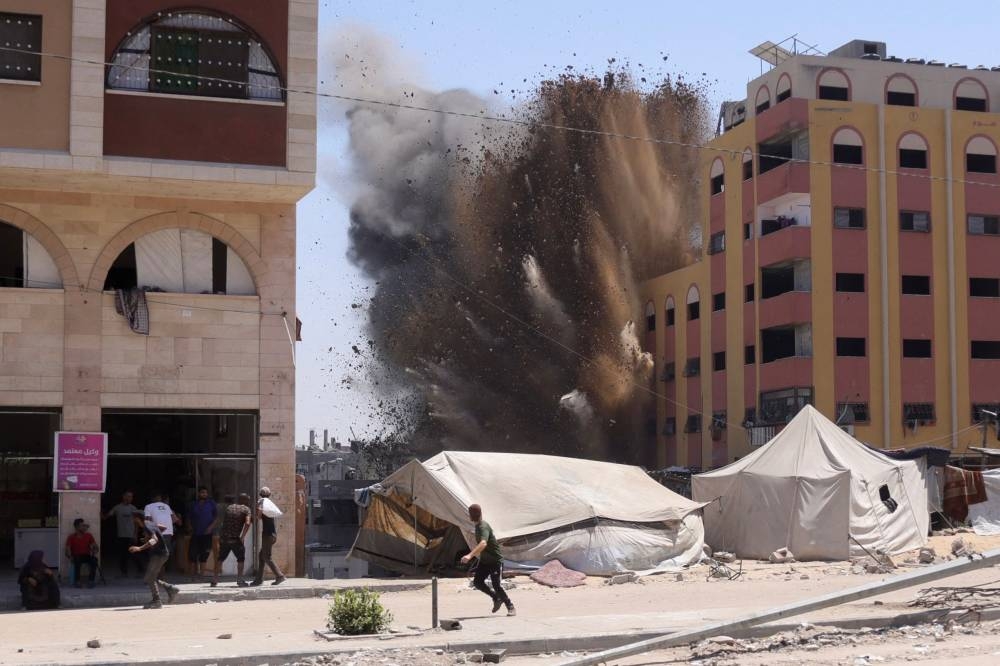 Palestinians rush for cover as smoke billows after an Israeli strike on a building in Jabalia in the northern Gaza Strip on August 20, 2025. (AFP)