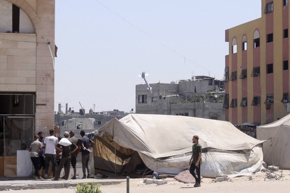 Palestinians watch as a rocket fired by an Israeli war plane targets a building in Jabalia in the northern Gaza Strip on August 20, 2025. (AFP)