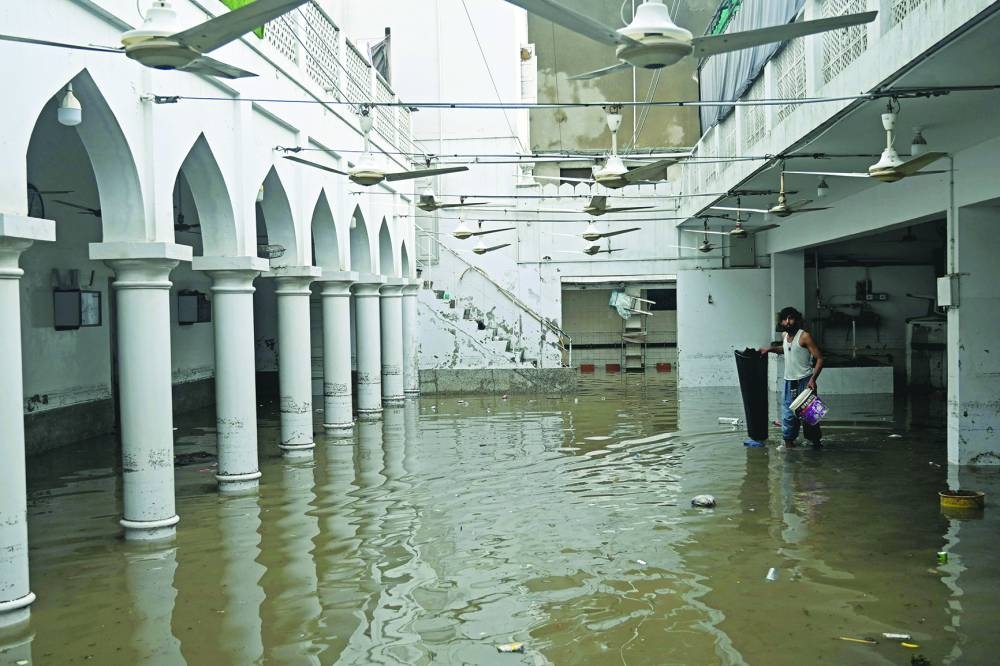 A man wades through the complex of a flooded mosque after heavy monsoon rains in Karachi Wednesday. (AFP)
