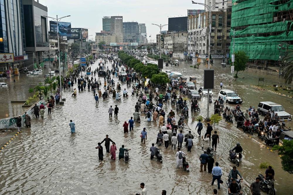 People wade through a flooded street after heavy rainfall in Karachi.